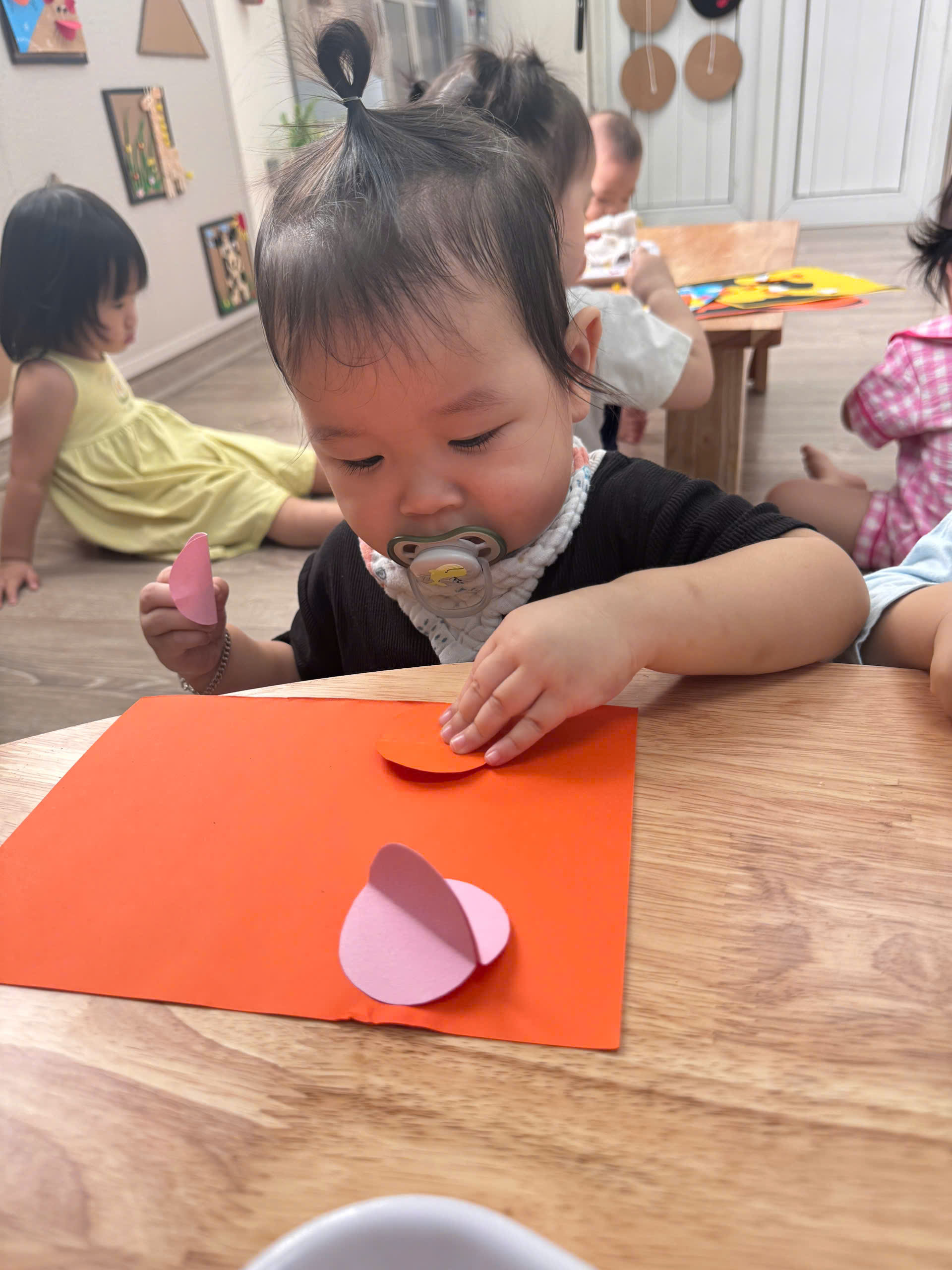 A baby sitting at a table with a paper cut outAI-generated content may be incorrect.