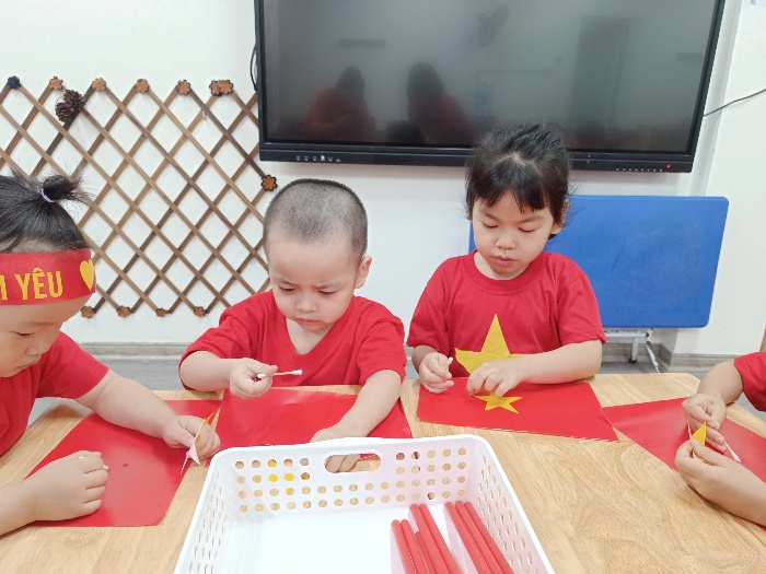 A group of children sitting at a table with red flags

AI-generated content may be incorrect.